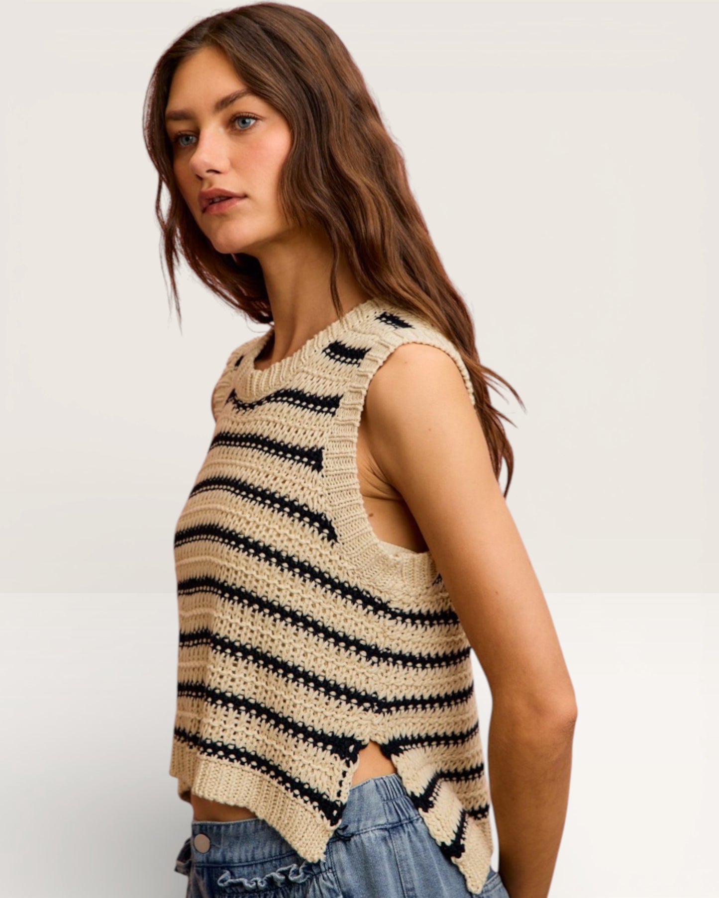 Woman wearing a sleeveless crochet top with black stripes on a white background