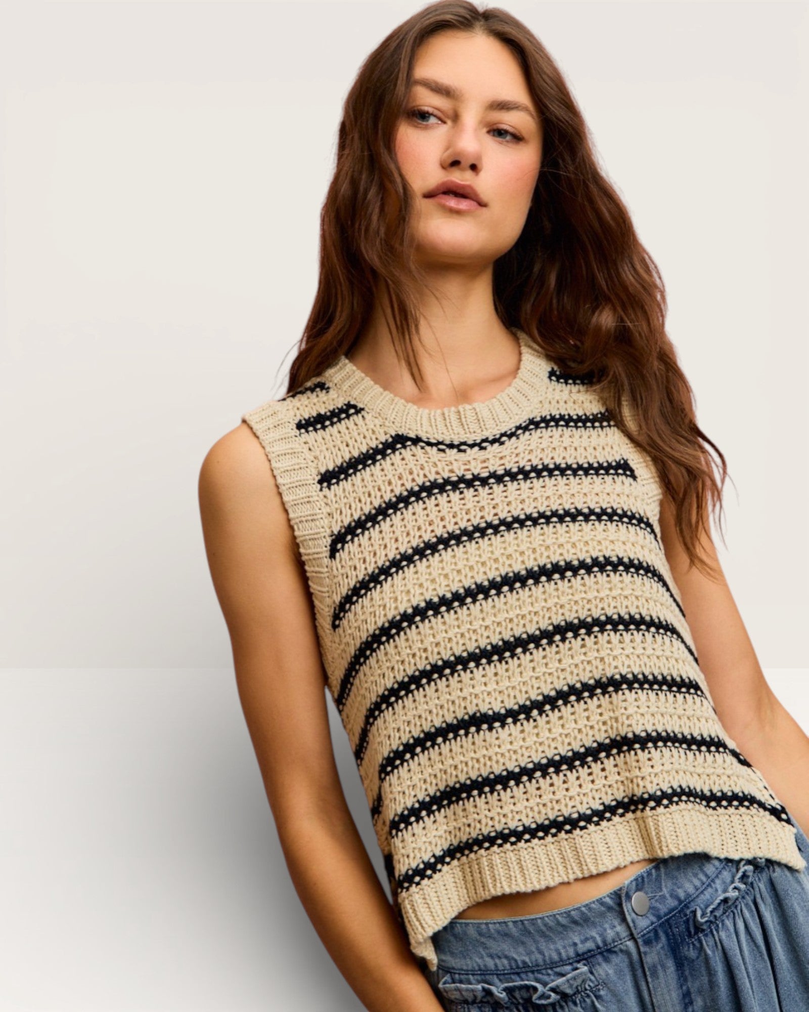 Woman wearing a striped sleeveless top with a plain background