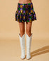 Person wearing a colorful checkered skirt and white boots on a beige background