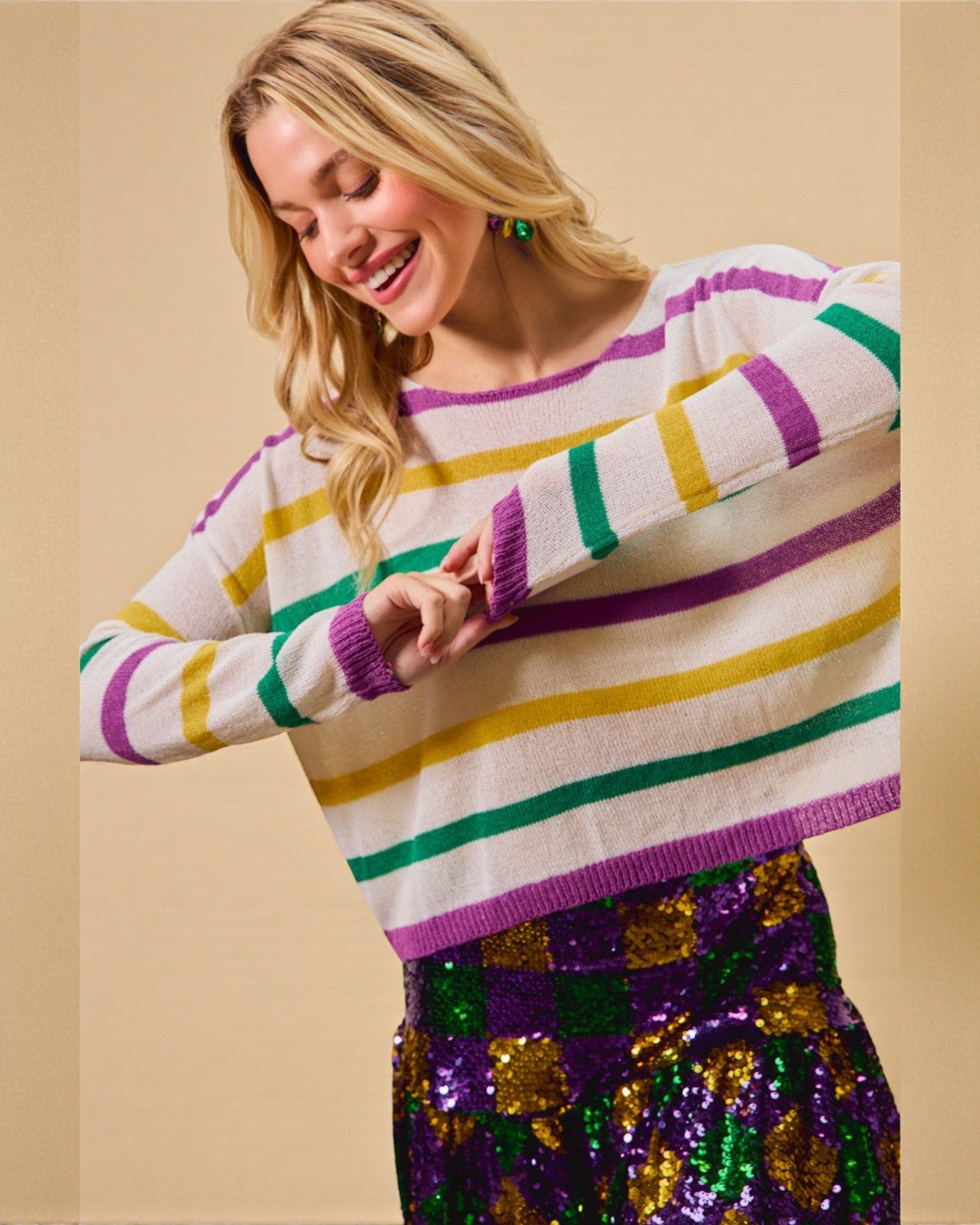 Woman wearing a colorful striped sweater with a checkered skirt on a beige background