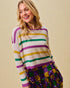Woman wearing a colorful striped sweater and sequin skirt against a beige background