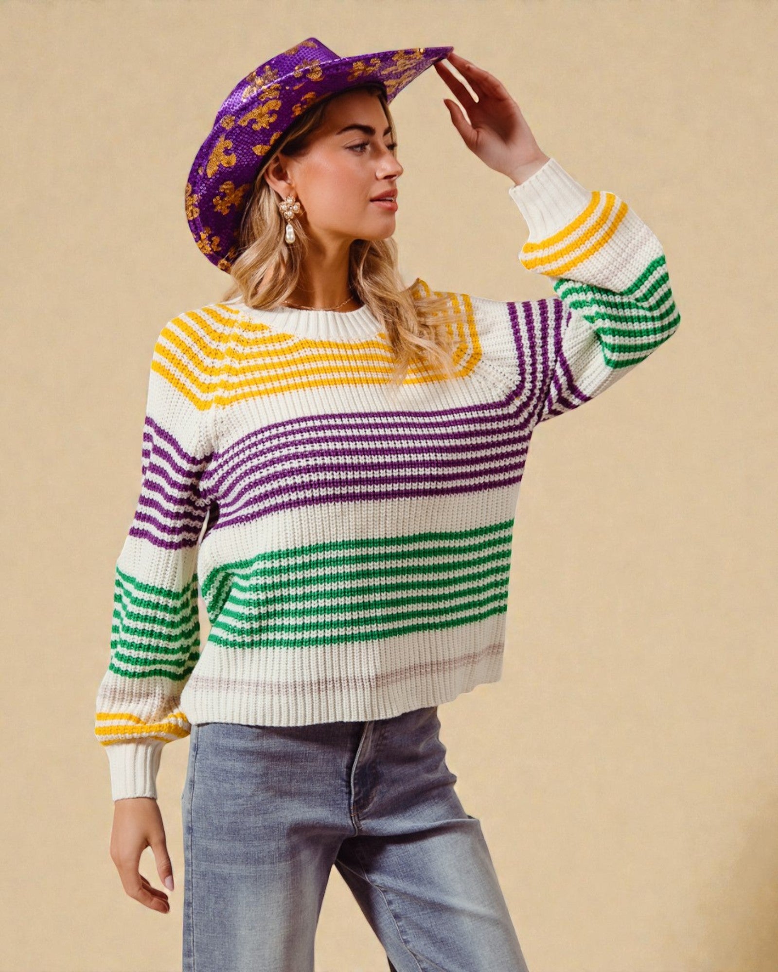 Person wearing a colorful striped sweater and purple hat against a beige background