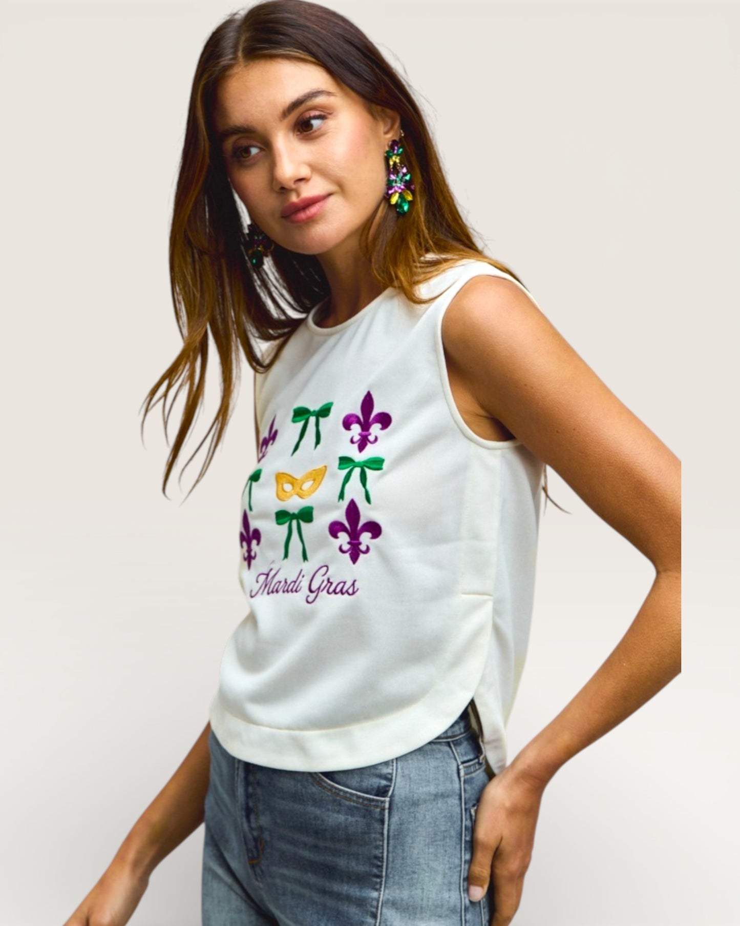 Woman wearing a white sleeveless top with colorful designs and 'Mardi Gras' text on a plain background