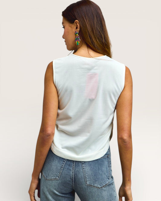 Woman wearing a light-colored sleeveless top with a pink patch on a plain background