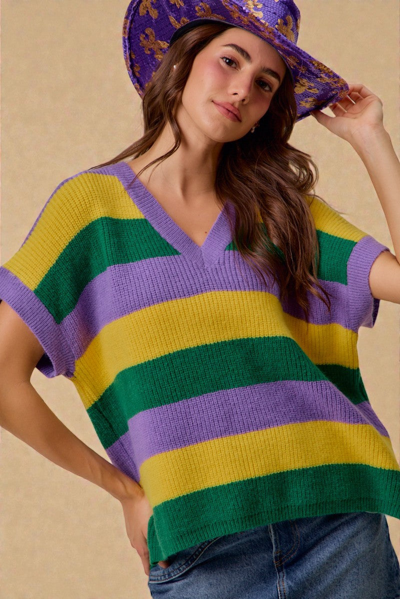 Woman wearing a colorful striped sweater and hat against a beige background