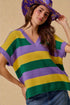 Woman wearing a colorful striped sweater and hat against a beige background
