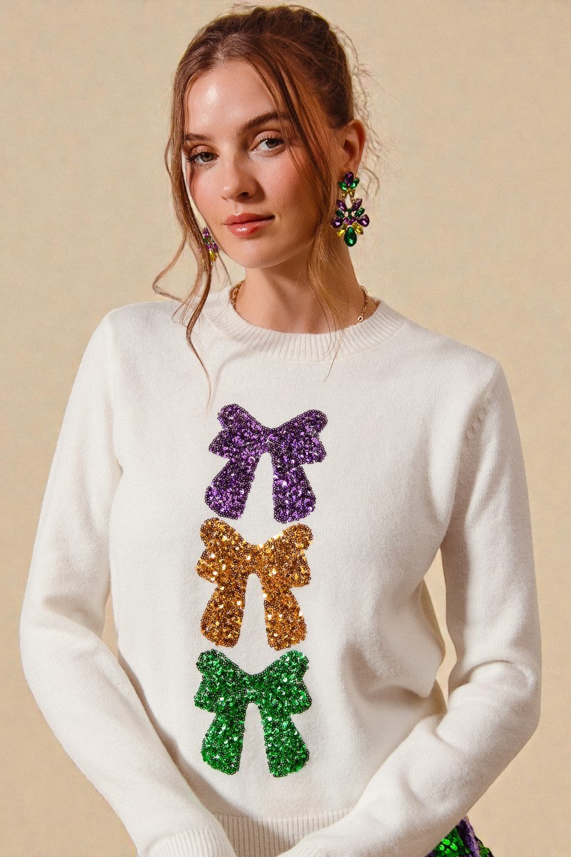 Woman wearing a white sweater with colorful bow designs on a beige background