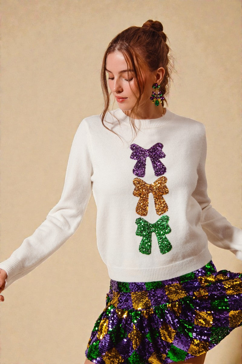 Woman wearing a white sweater with colorful sequin bows and a matching skirt on a beige background