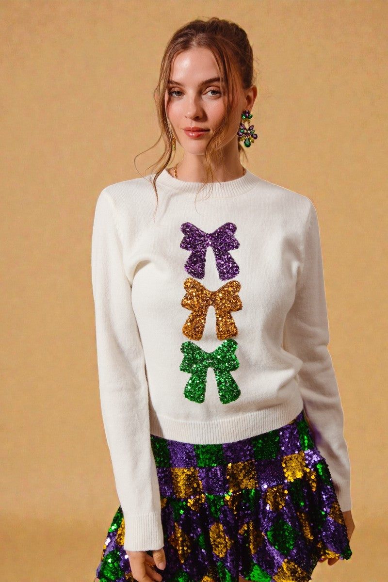 Woman wearing a white sweater with colorful bow designs and a multicolored skirt on a beige background
