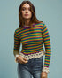 Woman wearing a colorful striped sweater with lace details on a light blue background