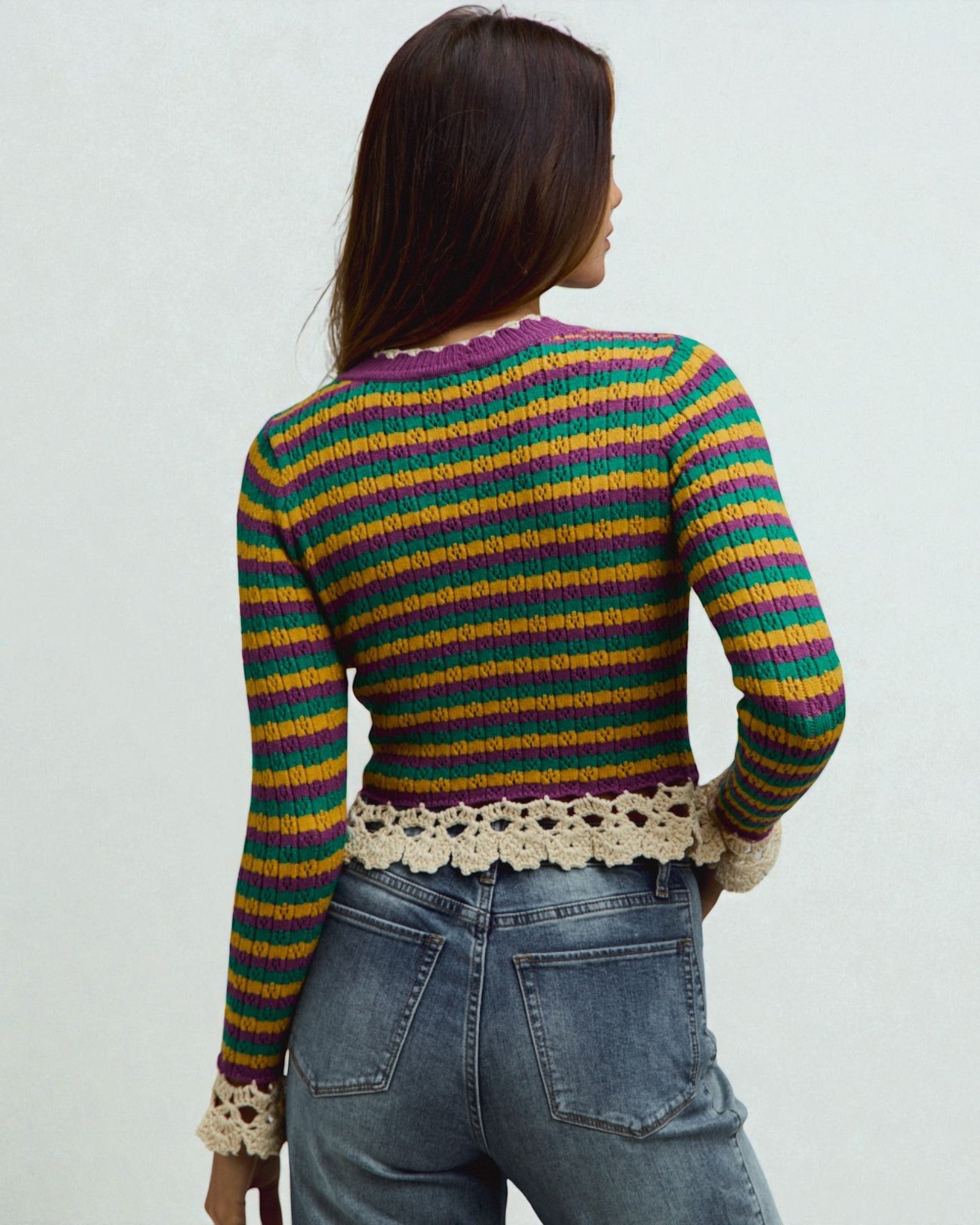 Person wearing a colorful striped sweater with lace details on a plain background