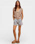 Woman wearing a beige sleeveless top and light blue shorts on a white background