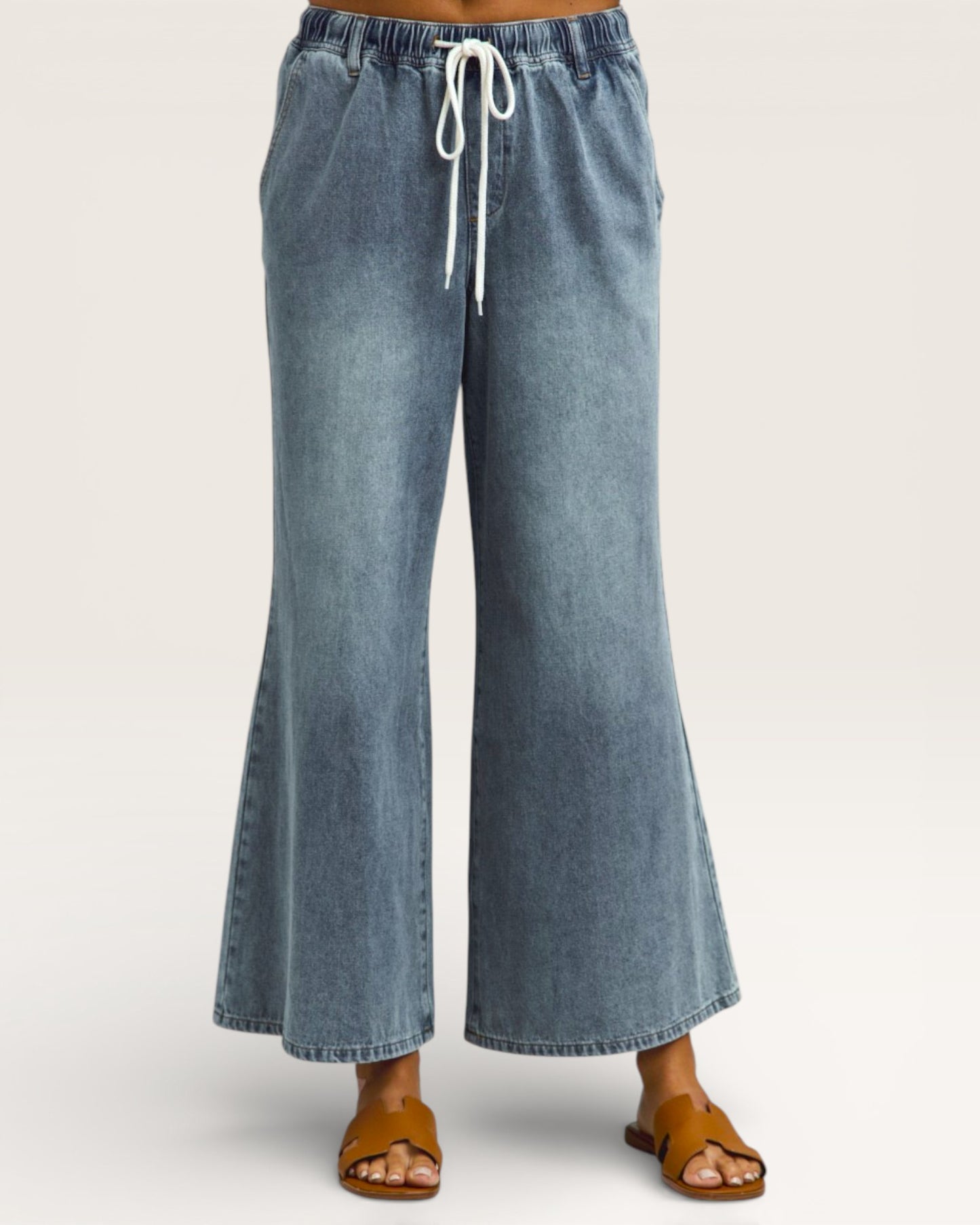 Blue denim wide-leg pants with a drawstring waist on a white background