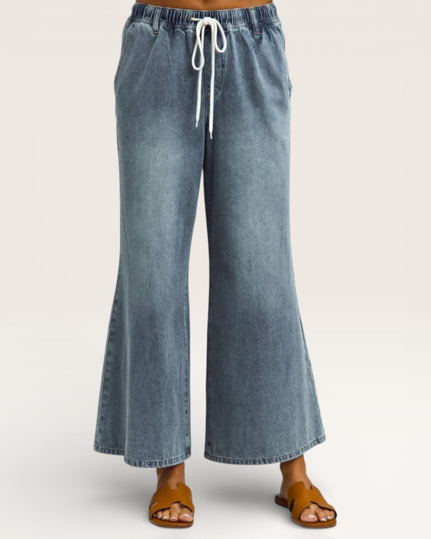 Blue denim wide-leg pants with a drawstring waist on a white background