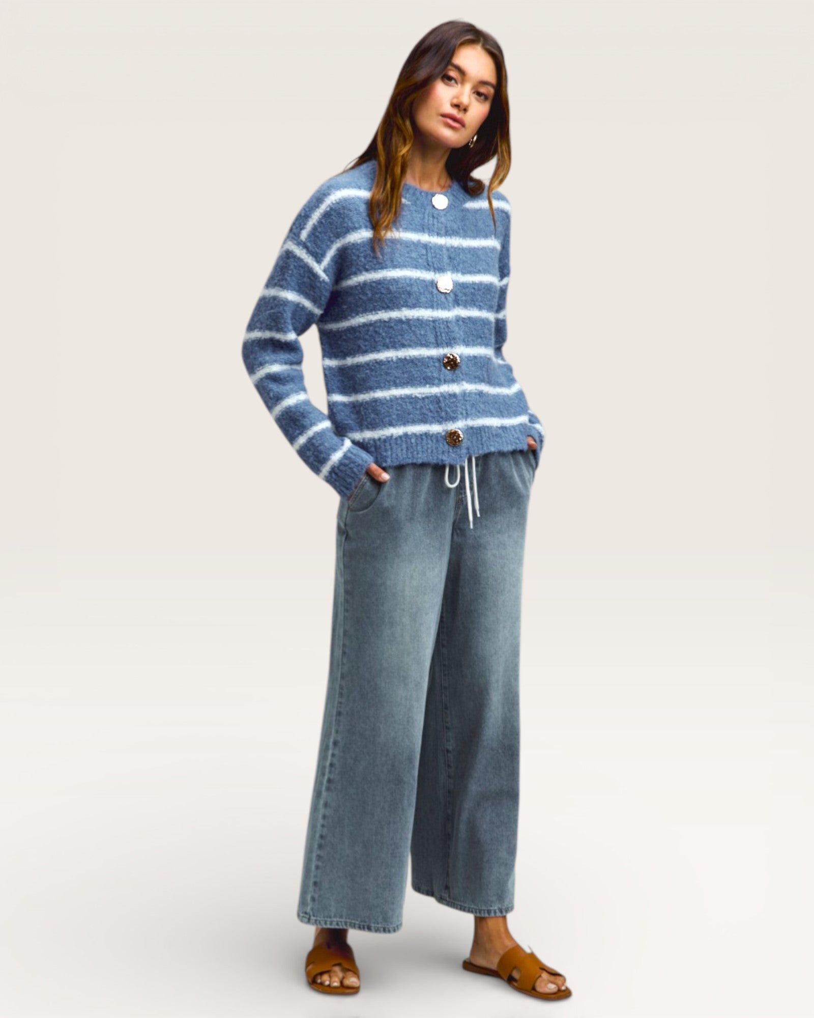 Woman wearing a blue striped sweater and jeans on a white background