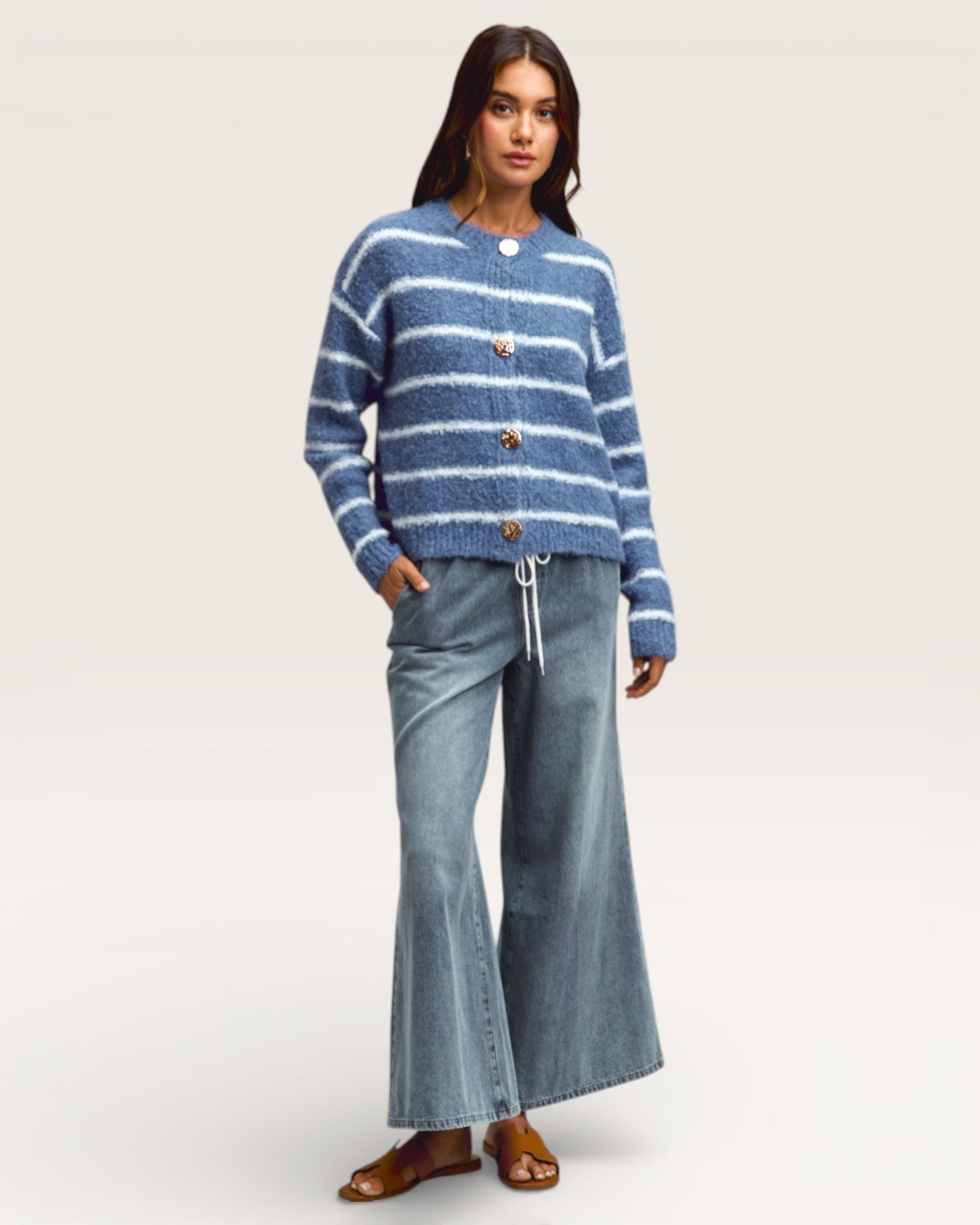 Woman wearing a blue striped sweater and jeans on a white background