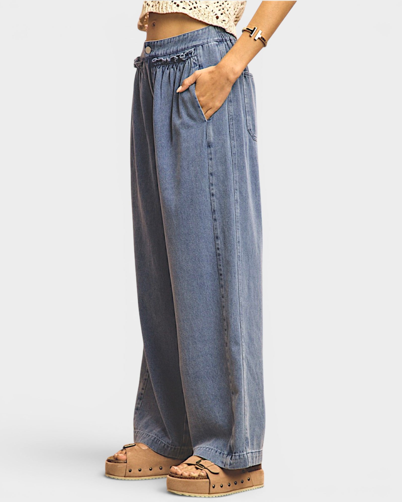Person wearing wide-leg blue jeans on a white background