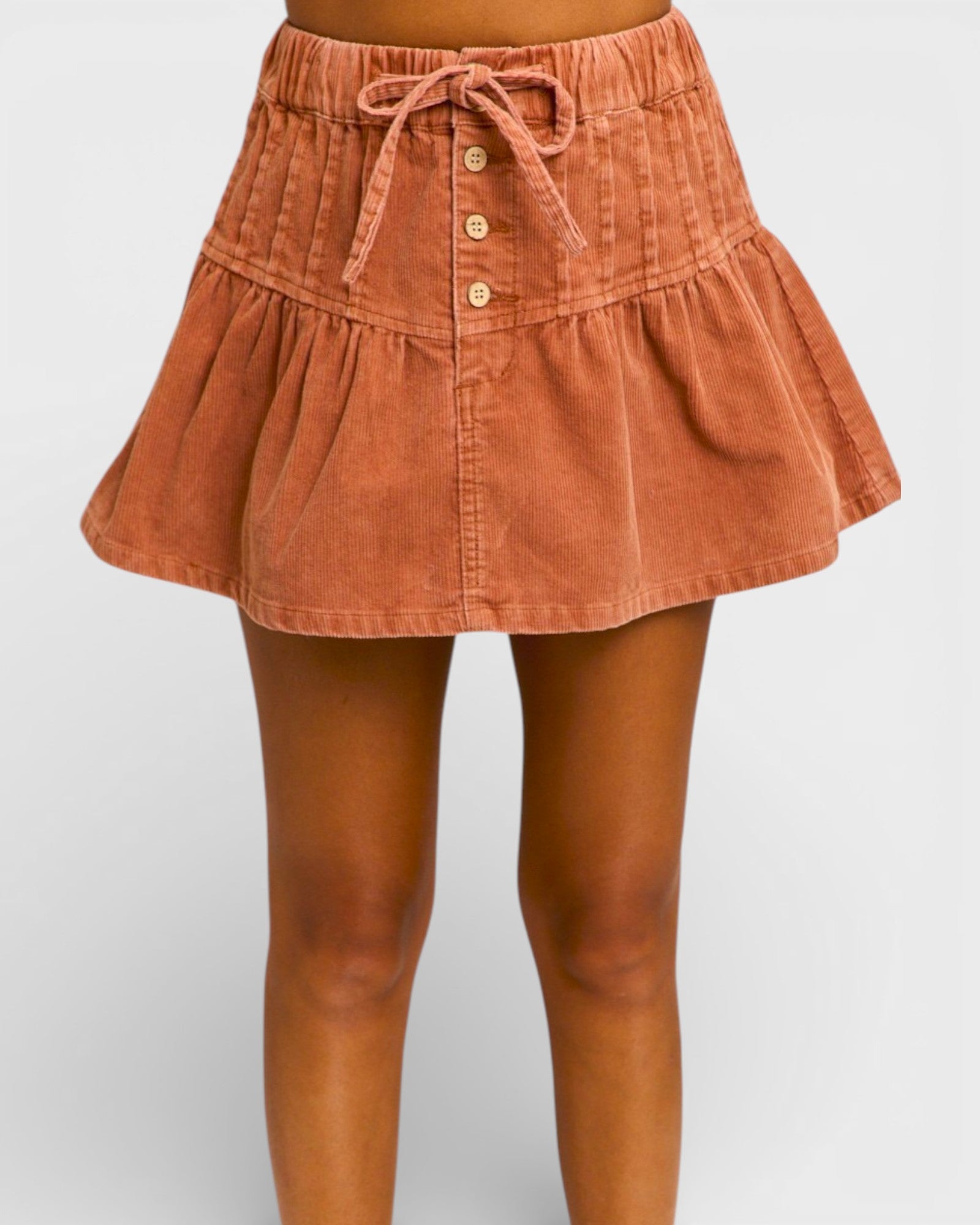 Brown corduroy skirt worn by a person on a plain background