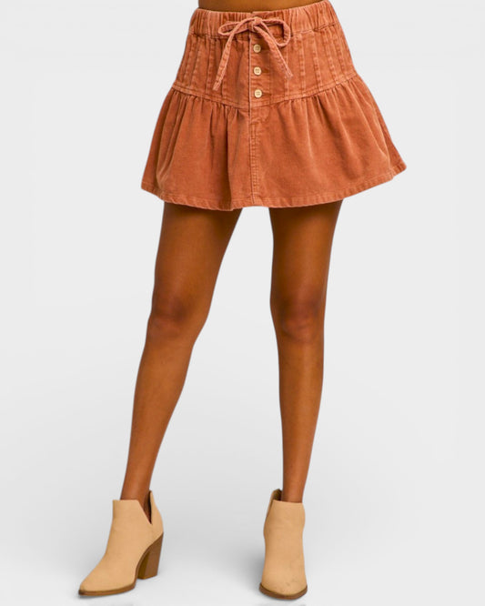 Brown denim skirt worn by a person on a white background