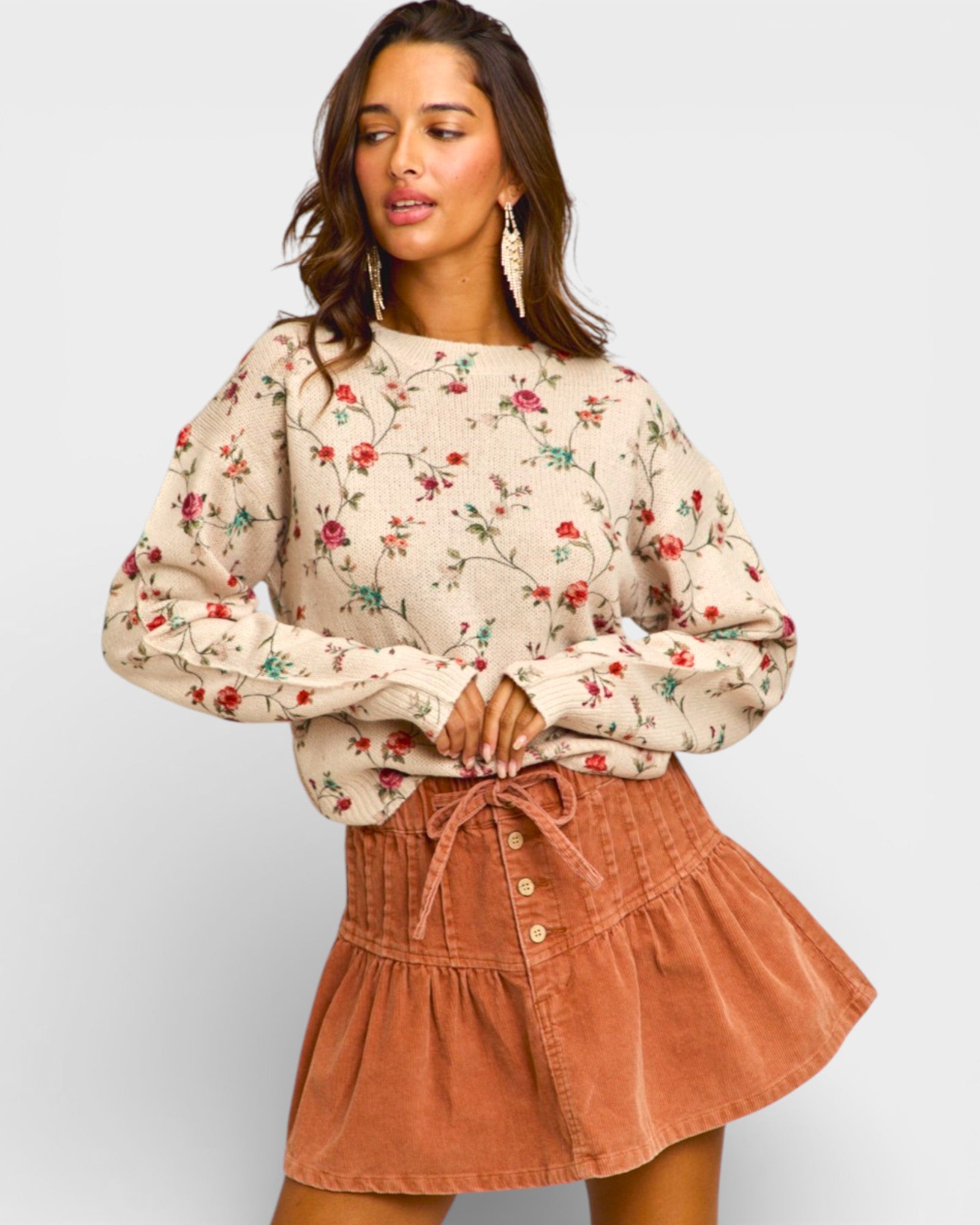 Woman wearing a floral blouse and brown skirt on a plain background