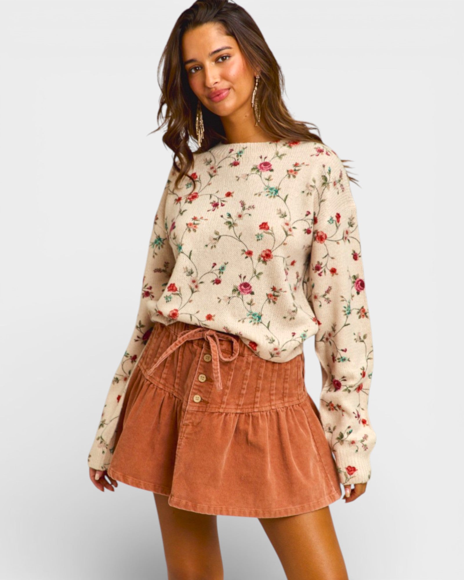 Woman wearing a floral long-sleeve top and brown skirt on a white background