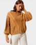 Woman wearing a brown cable knit sweater against a white background