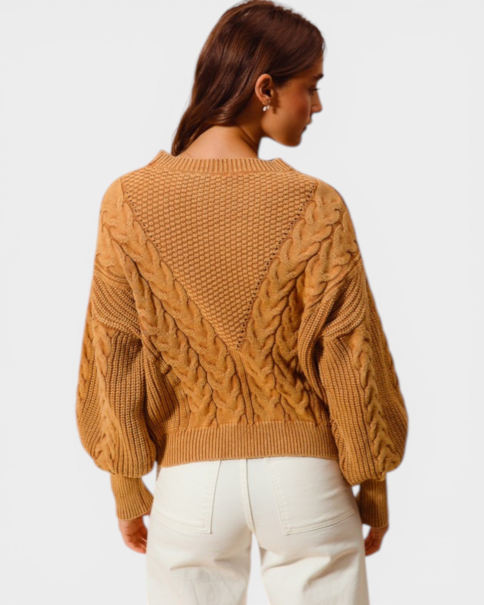 Person wearing a mustard yellow cable knit sweater on a plain background