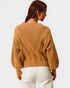 Person wearing a mustard yellow cable knit sweater on a plain background