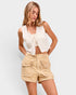 Woman wearing a white sleeveless top and beige shorts on a light gray background