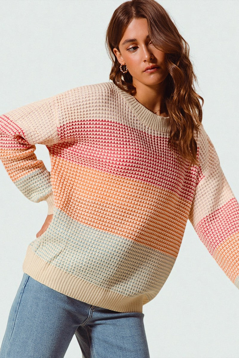Woman wearing a colorful striped sweater against a plain background