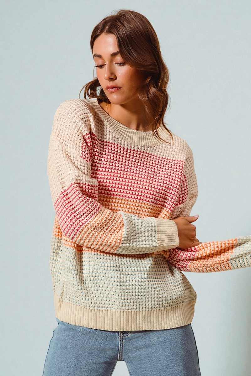 Woman wearing a colorful striped sweater against a plain background