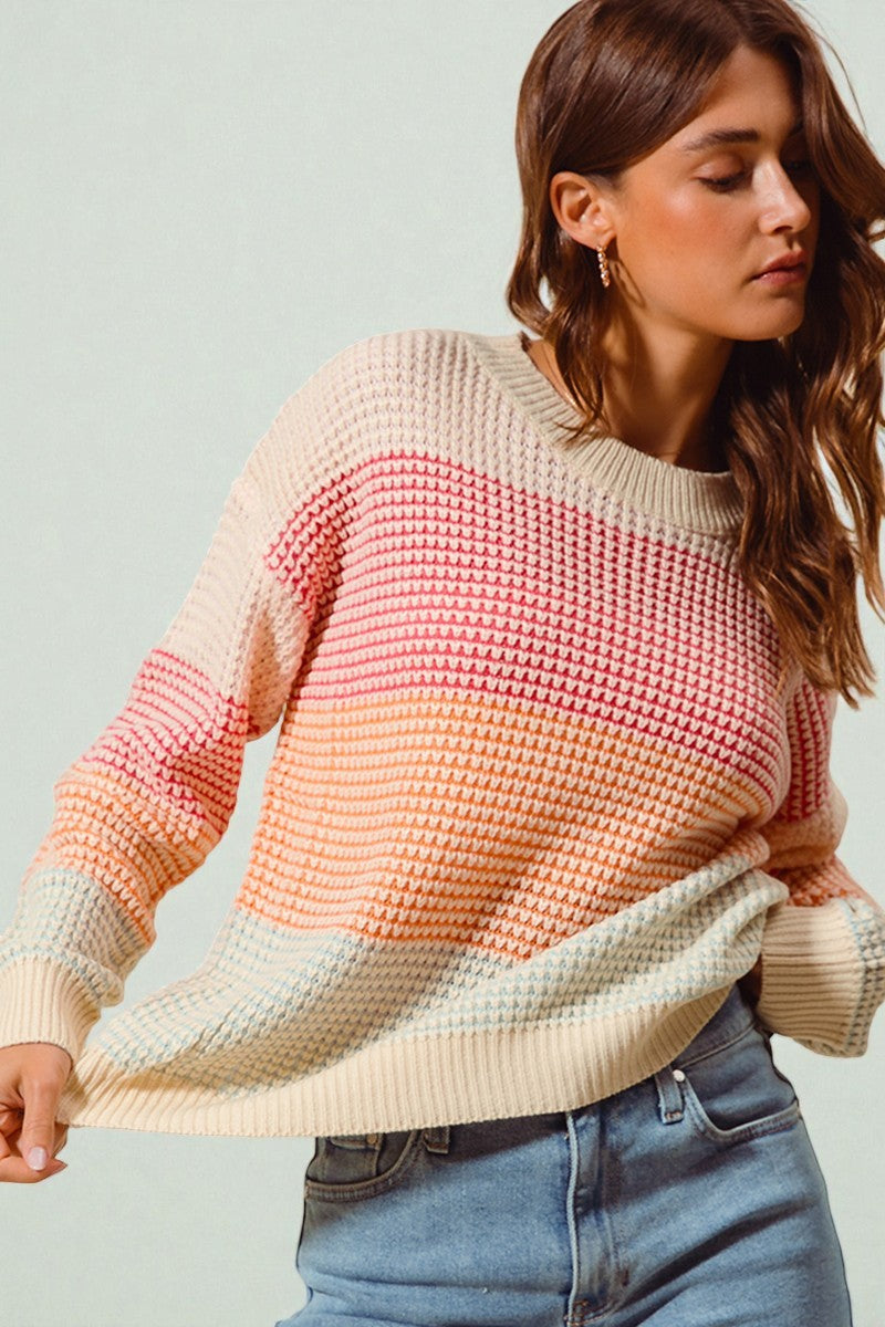 Woman wearing a colorful sweater with a gradient effect on a plain background