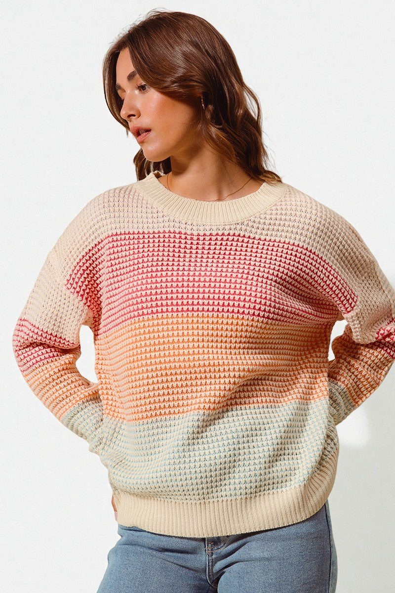 Woman wearing a colorful gradient sweater on a plain background