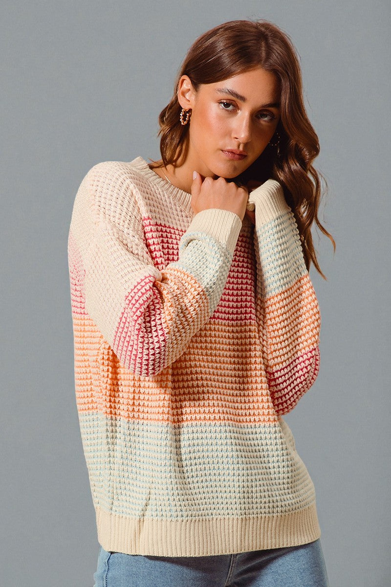 Woman wearing a colorful knit sweater against a gray background