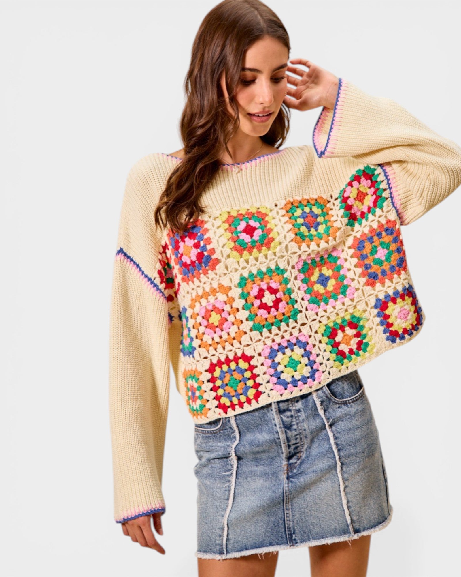 Woman wearing a colorful crochet sweater with a plain background