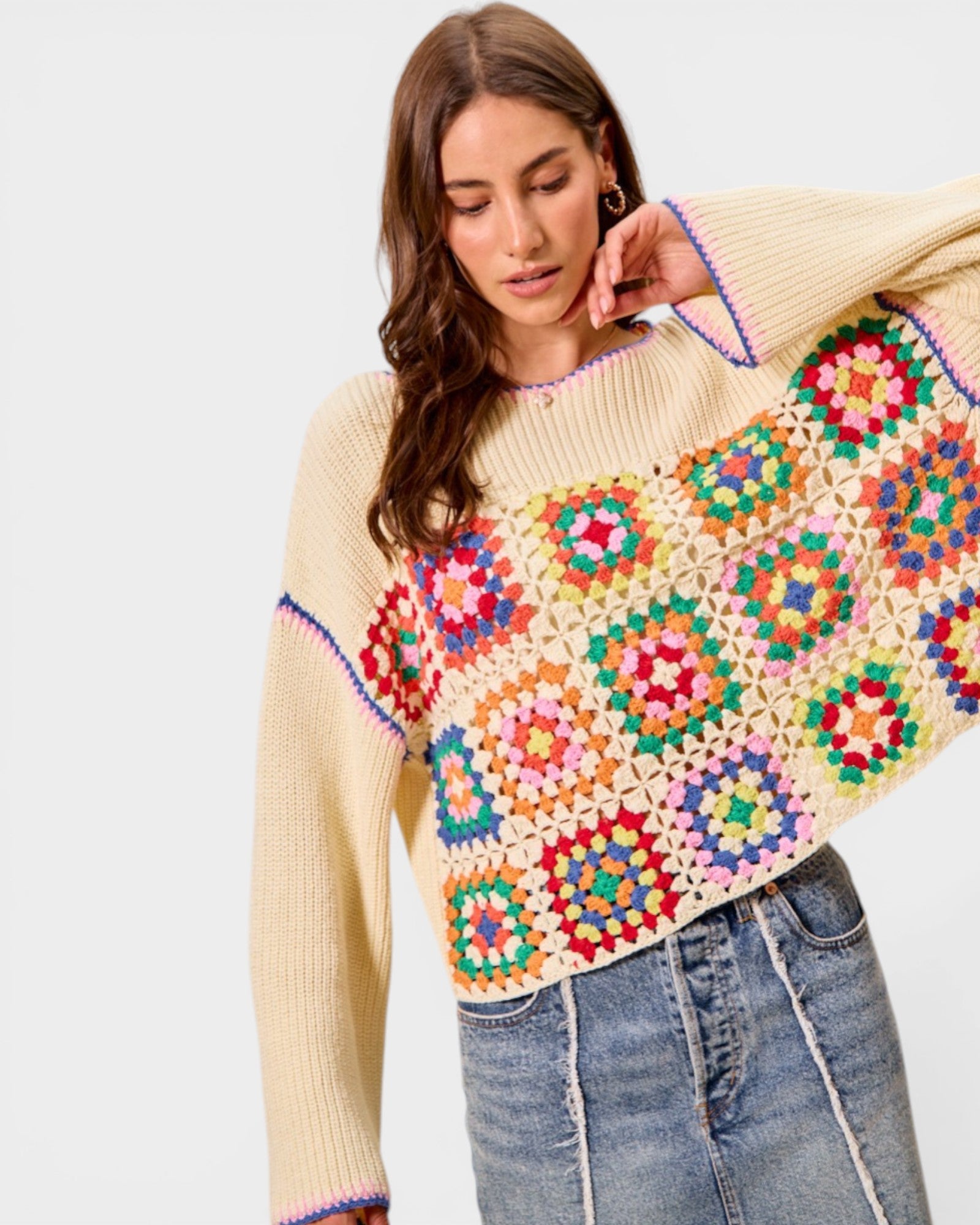 Woman wearing a colorful crochet sweater with a plain background