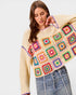 Woman wearing a colorful crochet sweater with a plain background