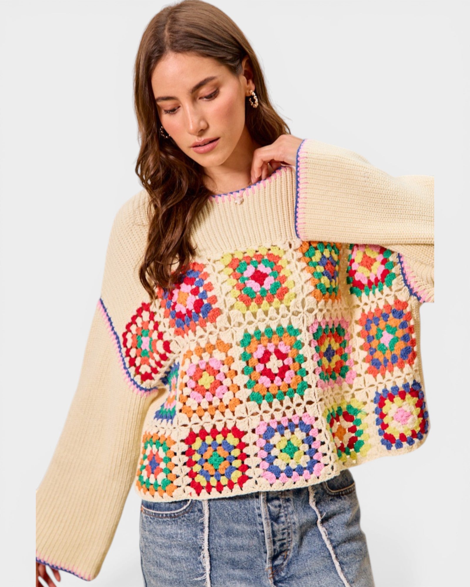 Woman wearing a colorful crochet sweater with a plain background