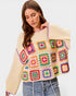 Woman wearing a colorful crochet sweater with a plain background
