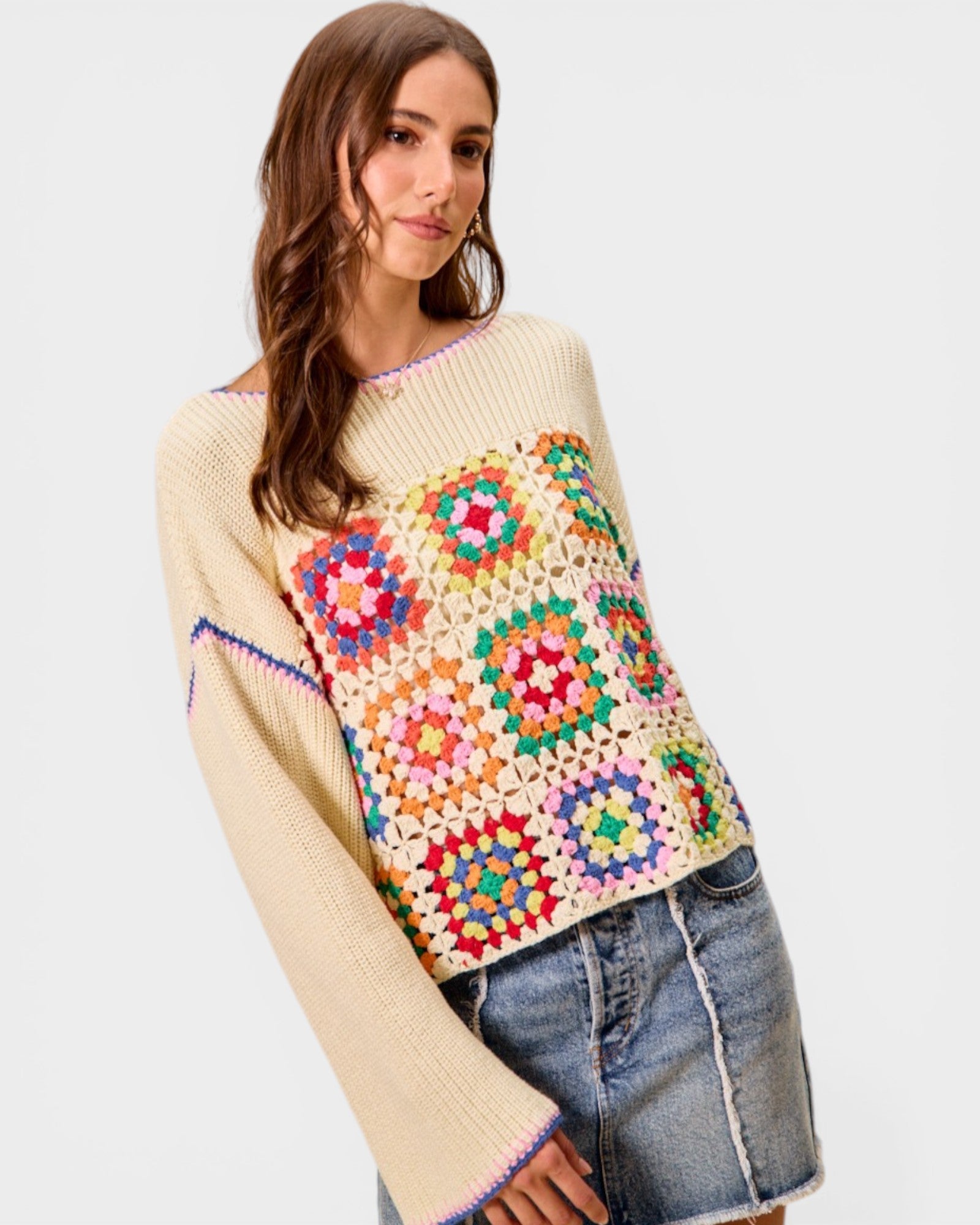 Woman wearing a colorful crochet sweater with a white background