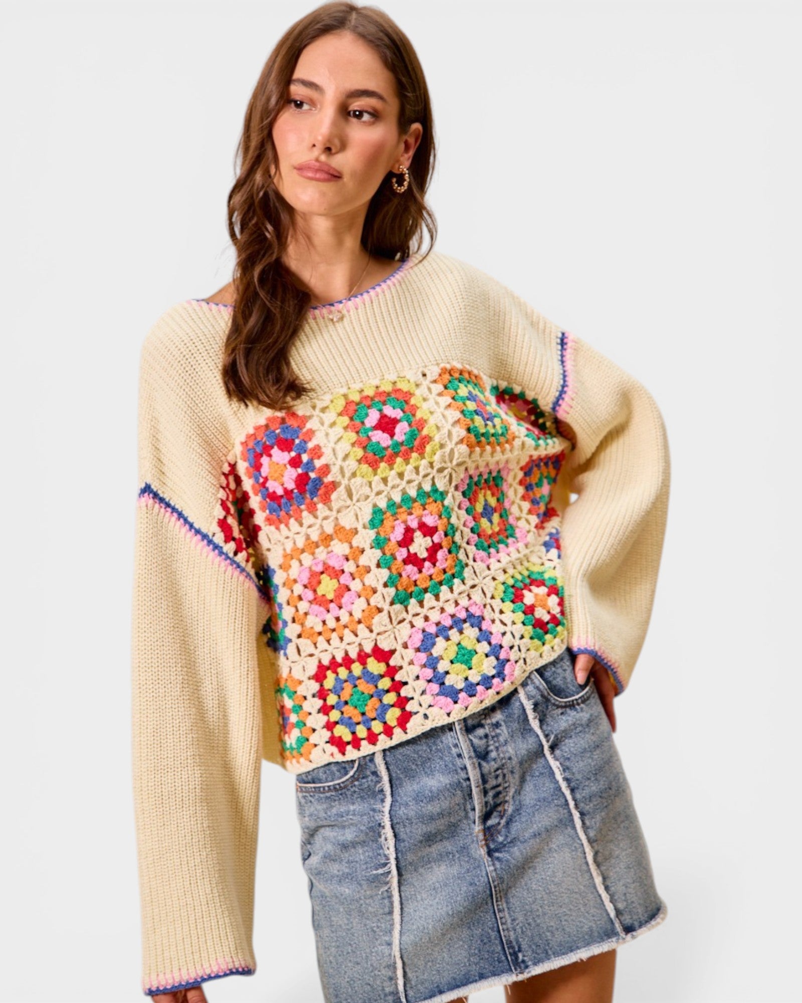Woman wearing a colorful crochet sweater with a plain background