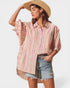 Woman wearing a striped shirt and denim shorts with a straw hat on a white background