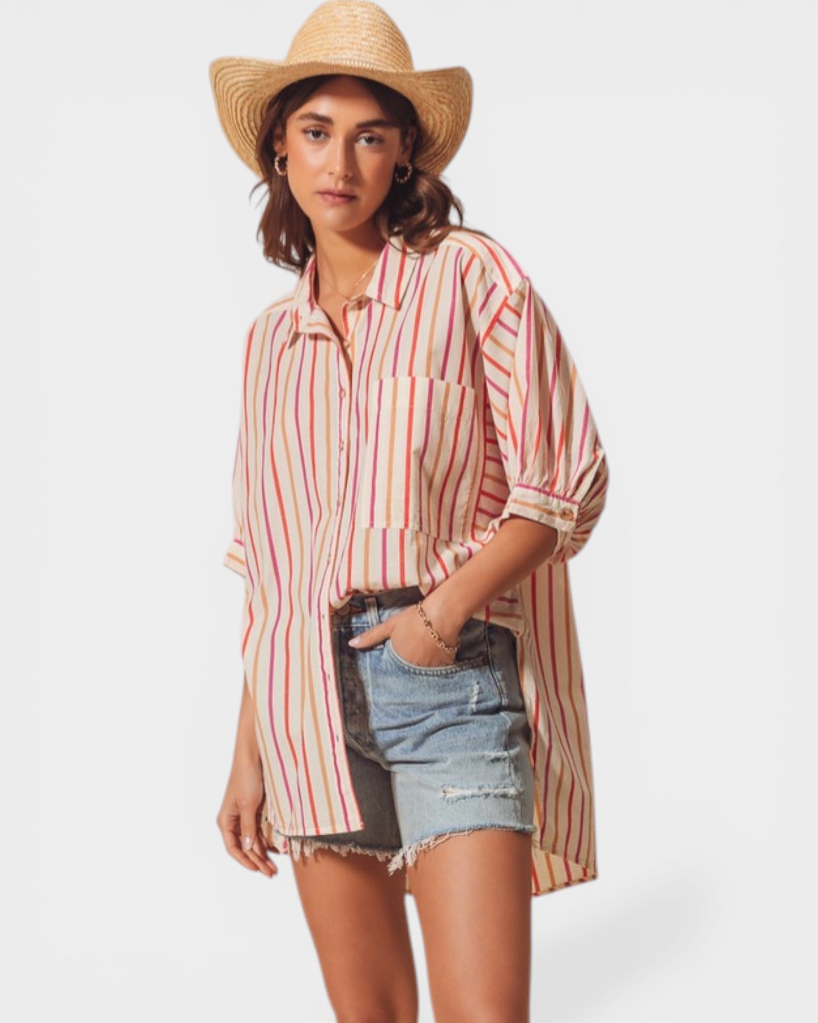 Woman wearing a striped shirt and denim shorts with a straw hat on a white background