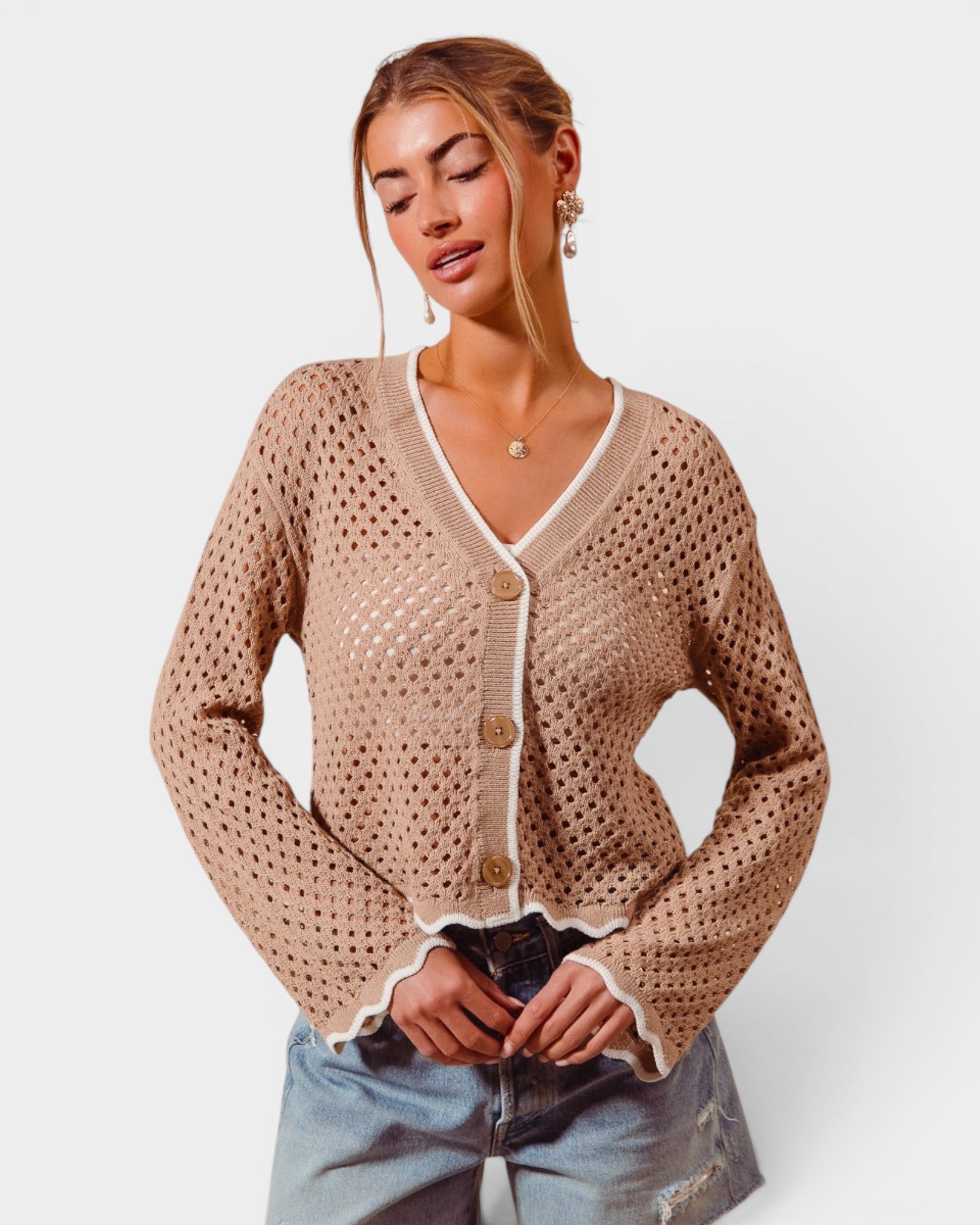 Woman wearing a beige open-knit cardigan with a white background