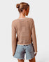 Woman wearing a beige knitted sweater and denim shorts on a white background