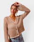 Woman wearing a beige crochet cardigan with white trim on a plain background