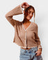 Woman wearing a beige crochet cardigan and denim shorts on a white background