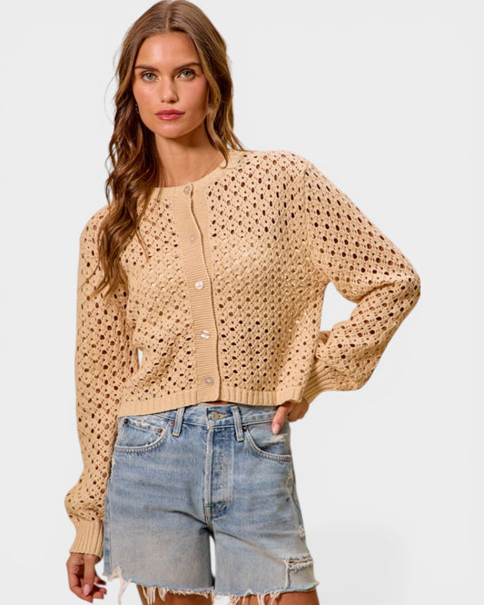 Woman wearing a beige cardigan and denim shorts on a white background