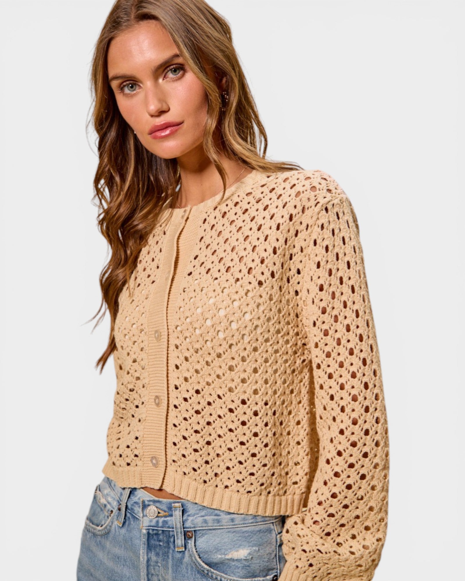 Woman wearing a beige open-knit cardigan on a white background