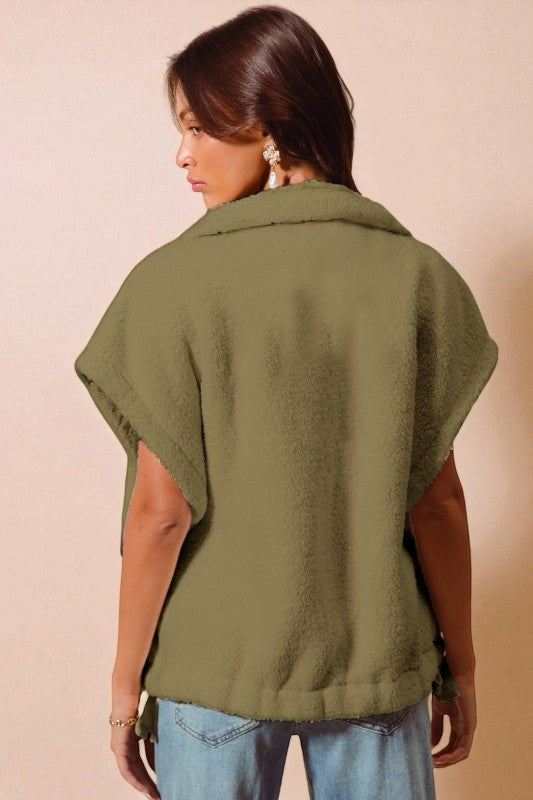 Person wearing a green poncho against a beige background
